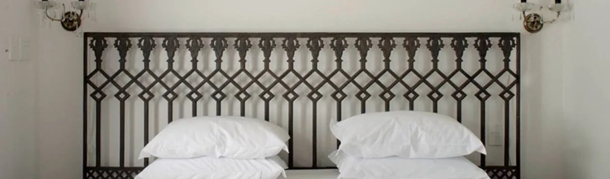 Cabeceira de ferro forjado e travesseiros brancos em um quarto do Zank Hotel Boutique